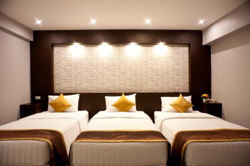 a bedroom with two beds with yellow pillows at Chateau de Sukhumvit in Bangkok