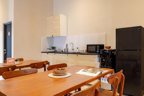 a kitchen with a wooden table and a black refrigerator at Cove Chara in Jimbaran