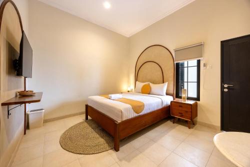 a bedroom with a bed and a tv in it at Cove Chara in Jimbaran