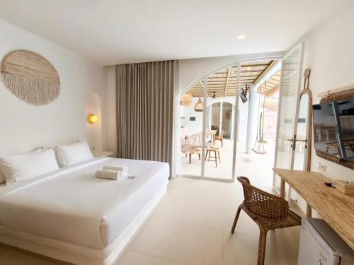a bedroom with a large white bed and a table at Khaiyyara Jimbaran Bali in Uluwatu