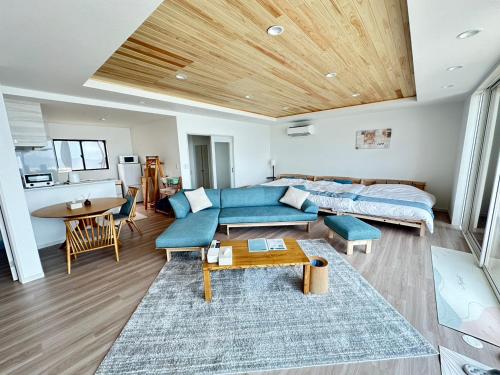 a living room with a blue couch and a bed at Lapita Resort in Sakai