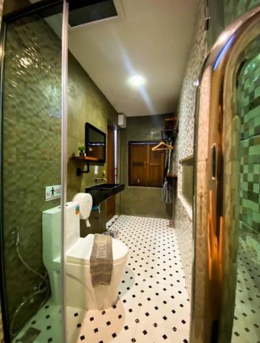 a bathroom with a toilet and a tiled floor at บ้านเคียงสะหวัน in Muang Phaluka