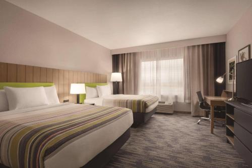 a hotel room with two beds and a desk at Country Inn & Suites by Radisson, Oklahoma City - Bricktown, OK in Oklahoma City