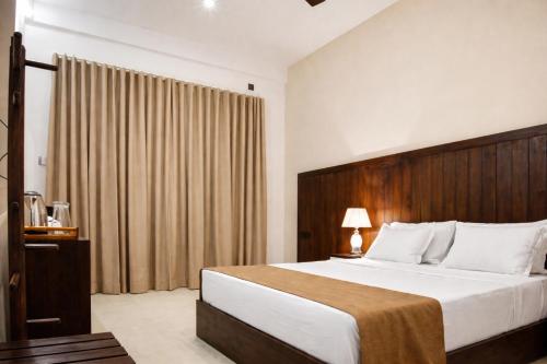 a bedroom with a large bed with a wooden headboard at Jackhill Hiriketiya in Dickwella