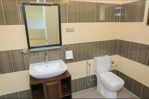 ein Badezimmer mit Toilette, Waschbecken und Spiegel in der Unterkunft Yatra Negambo in Katunayaka