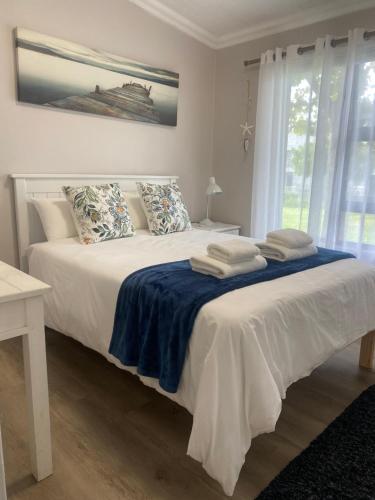 a bedroom with a white bed with towels on it at Living Lite 1 and 2 in Kleinmond