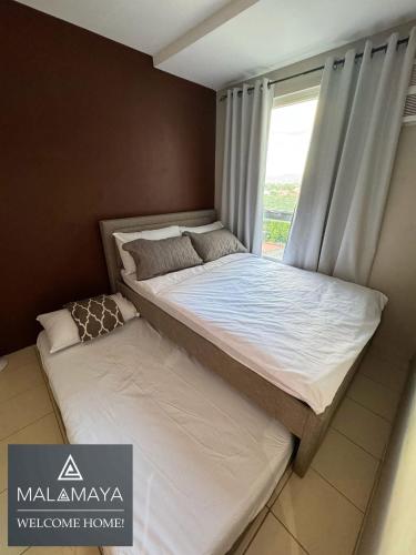 a bed in a room with a window at Malamaya Staycation in Manila