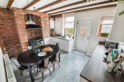 a kitchen with a table and a brick wall at Helter Skelter Matlock in Matlock