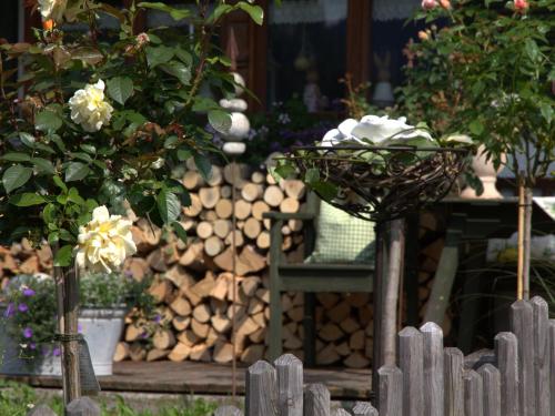 a garden with a pile of logs and a basket of flowers at Gästehaus Barbara Schwaiger - Chiemgau Karte in Inzell