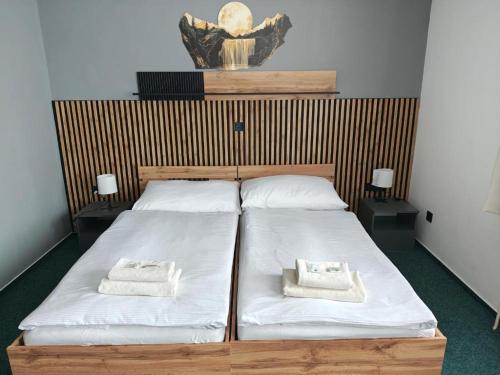two beds in a room with white sheets and towels at HOTEL Tyrapol - izby in Oravská Lesná