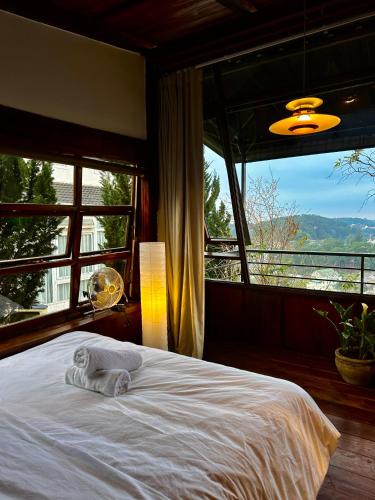 a bedroom with a white bed with a large window at SIA Home - Dalat Haus in Ấp Ða Lợi