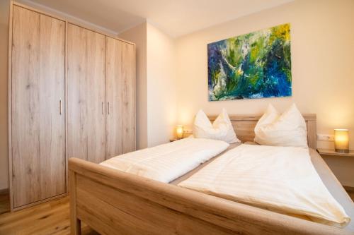 a bedroom with a large bed with a painting on the wall at Rebenhof Schwalm in Herrnbaumgarten