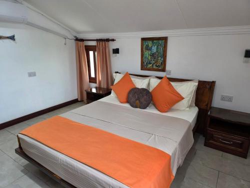 a bedroom with a large bed with orange pillows at The Drake Seaside Apartment in Bel Ombre