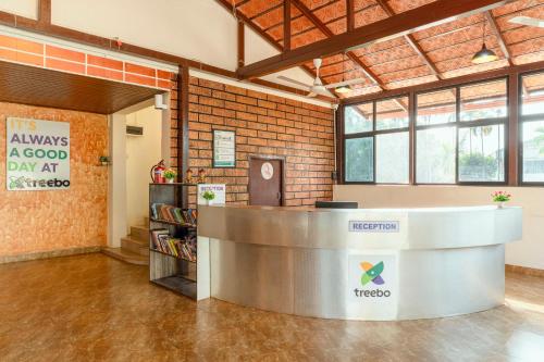 an office with a reception counter and a brick wall at Treebo Pratham Inn Water Park Resort With Swimming Pool in Kundapur