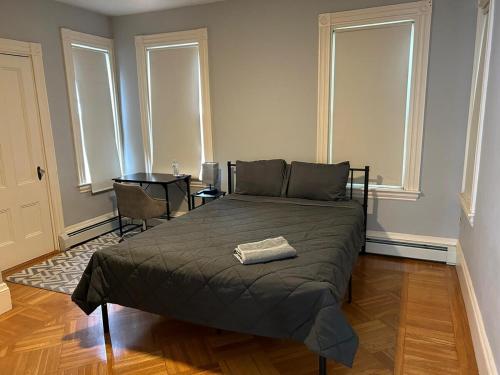 a bedroom with a bed and a table and windows at HomeStay in Harvest Street in Boston