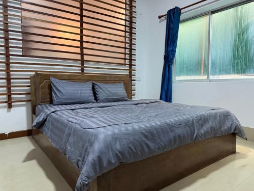 una camera da letto con un letto con lenzuola blu e finestre di White Castle Hotel a Siem Reap