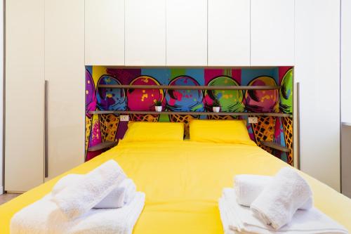 a bedroom with a yellow bed with two towels at Black & White or Pop Art - Design Apartments with Parking & WiFi in Saronno