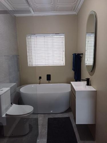 a bathroom with a tub and a toilet and a sink at Oystercatcher Guest House in Wilderness