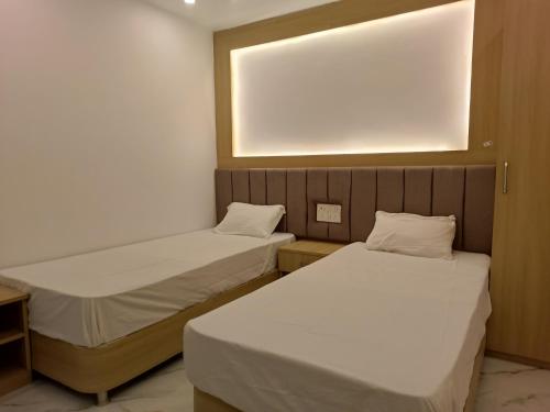 two beds in a small room with a light on the wall at Hotel Niko International in Bodh Gaya