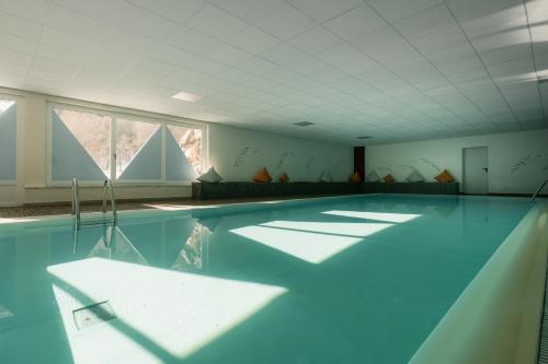 a swimming pool with blue water in a room with windows at Sporthotel Kurzras in Maso Corto