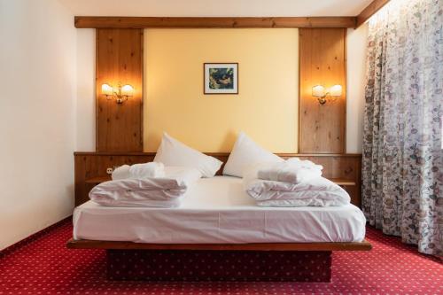 a bedroom with a bed with white sheets and pillows at Sporthotel Kurzras in Maso Corto