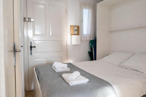 a white bedroom with two towels on a bed at Studio cabine climatise Malibu Village in Canet-en-Roussillon