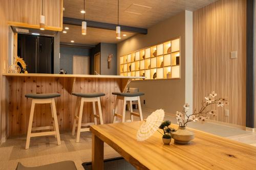 a kitchen with a bar with stools and a table at JAPAVISTA Yumeno in Osaka