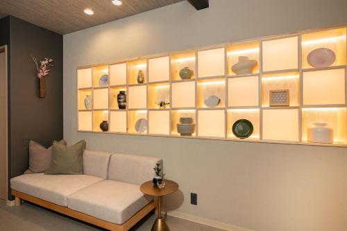 a living room with a couch and a shelf with dishes at JAPAVISTA Yumeno in Osaka