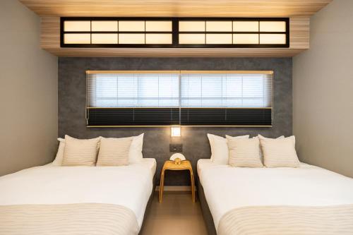 two twin beds in a room with a window at JAPAVISTA Yumeno in Osaka