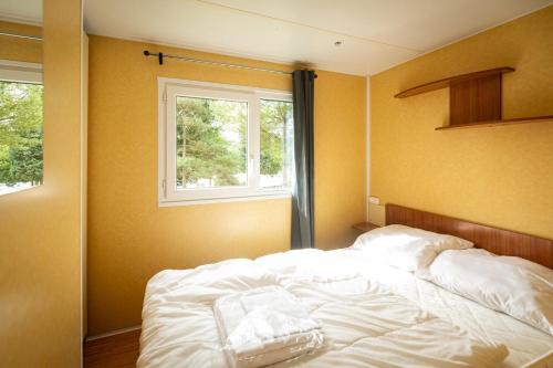 a bedroom with a white bed with a window at Camping ArdenParks La Petite Suisse - Maeva Vacansoleil in Manhay