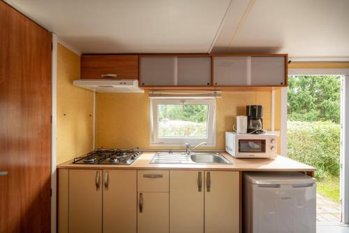 a small kitchen with a sink and a microwave at Camping ArdenParks La Petite Suisse - Maeva Vacansoleil in Manhay
