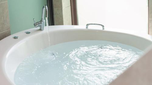 a bath tub filled with water with a faucet at Namhae Briant Oceanview Spa Pension in Namhae