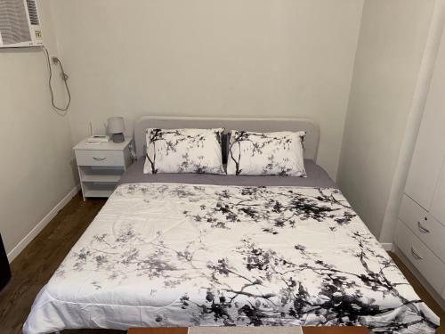 a bedroom with a bed with a black and white comforter at Priscilla Suites Mactan by Amani Grand Resort in Mactan Cebu International