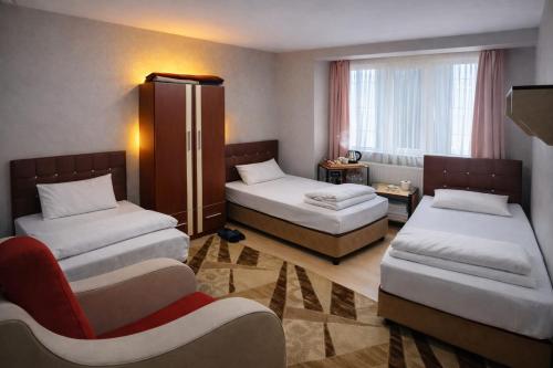 a hotel room with two beds and a chair at Arı Otel in Erzurum