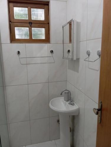 a white bathroom with a sink and a mirror at Casa Recanto do Sossego in Antonina