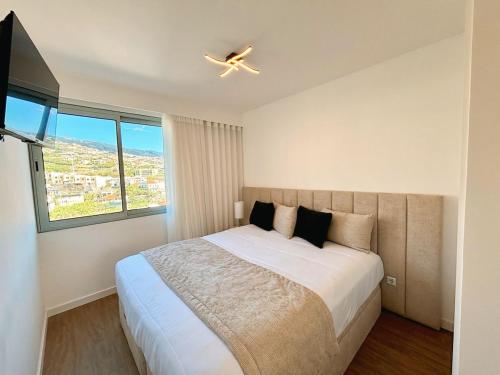 a bedroom with a large bed with a ceiling fan at Star Light Apartment in Câmara de Lobos