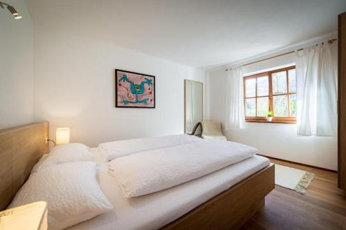 a large bed in a white room with a window at Ferienhaus-Pitztal in Wenns