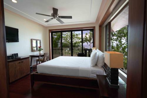 a bedroom with a bed and a large window at El Mar Resort in Sampong