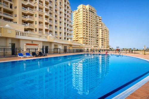 una piscina frente a dos edificios altos en The Sandstone Studio, en Ras al Khaimah