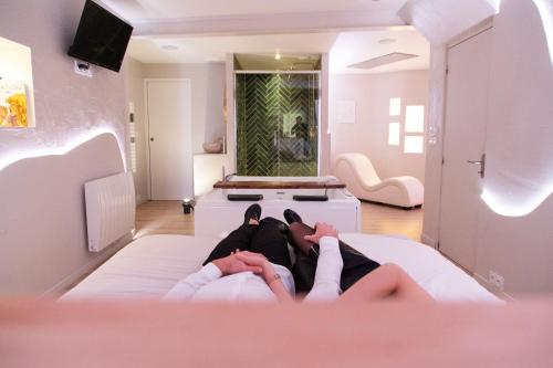 two people laying on a bed in a room at Les Jolies Nuits - À la folie, Loft & Spa in Montrevault