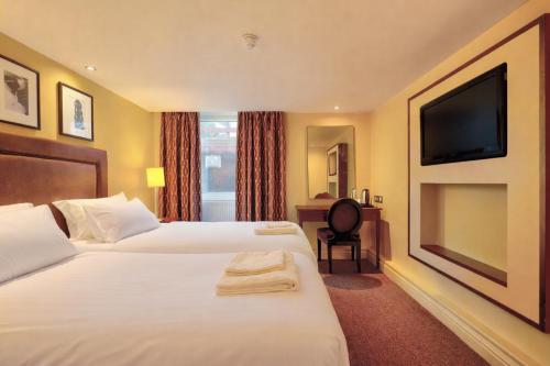 a hotel room with two beds and a flat screen tv at Manchester Airport Stanley Hotel by Belvilla in Handforth