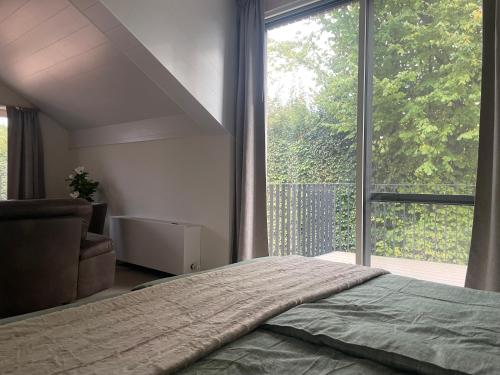 a bedroom with a bed and a large window at Le Grand Pont in Vielsalm