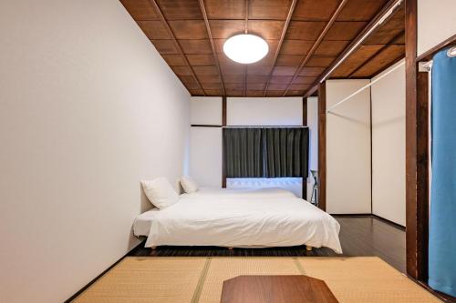a bedroom with a white bed and a wooden ceiling at YAGARA TERRACE HOUSE OSAKA Room A in Osaka