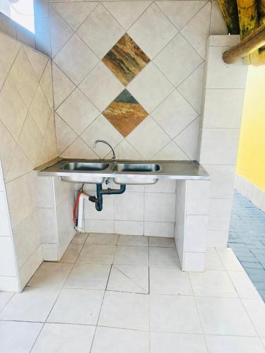a bathroom with a sink and a tile wall at Druza’s guest house in Rustenburg