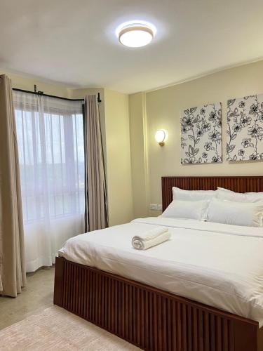 a bedroom with a large white bed with a window at Jenn Suites - Nakuru Town in Nakuru