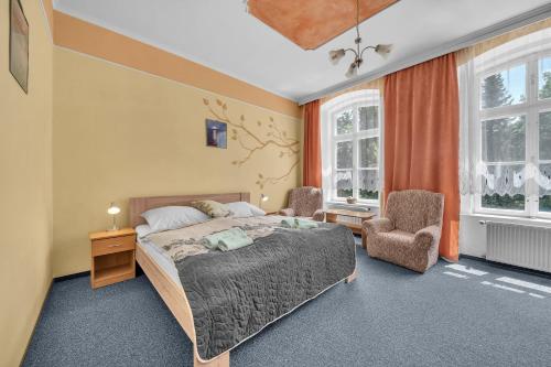 a bedroom with a bed and two chairs at Lázeňský dům Erika in Františkovy Lázně