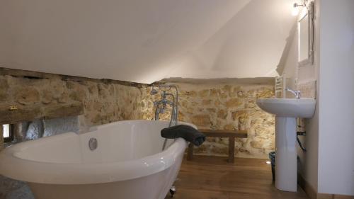 a bathroom with a white bath tub and a sink at Le Moulin du Clapier- Gîte La Banette in Sorges