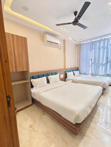 a bedroom with two beds and a ceiling fan at Hotel Sanskar Palace in Godarpura