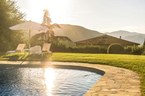 a pool in a yard with two chairs and an umbrella at Romantic Apartment With Tuscan Valley Views in Londa