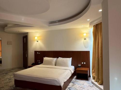 a bedroom with a large bed and a large window at Coral Hotel Karbala in Karbala